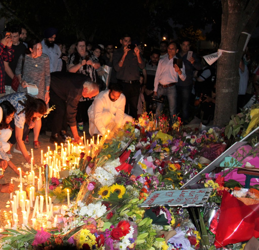 People lighting memorial candles at a service in the street